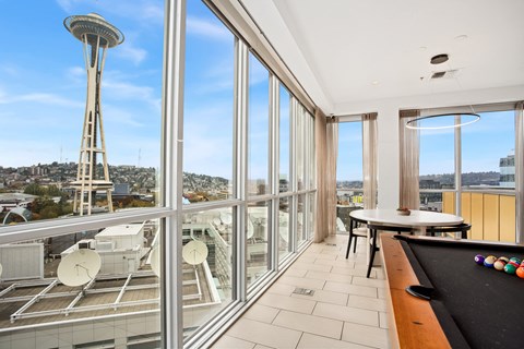 a room with a view of the space needle and a pool table