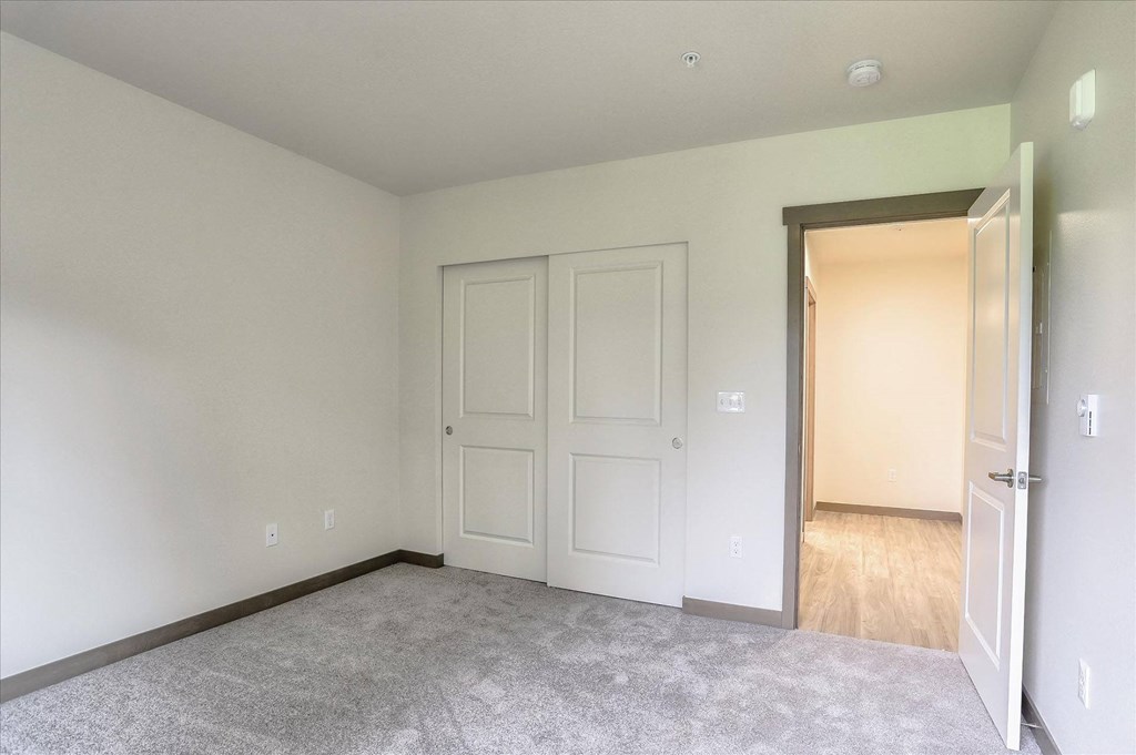 a bedroom with white walls and a door to a hallway