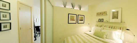 A bedroom with a bed, a mirror, and a few pictures on the wall.