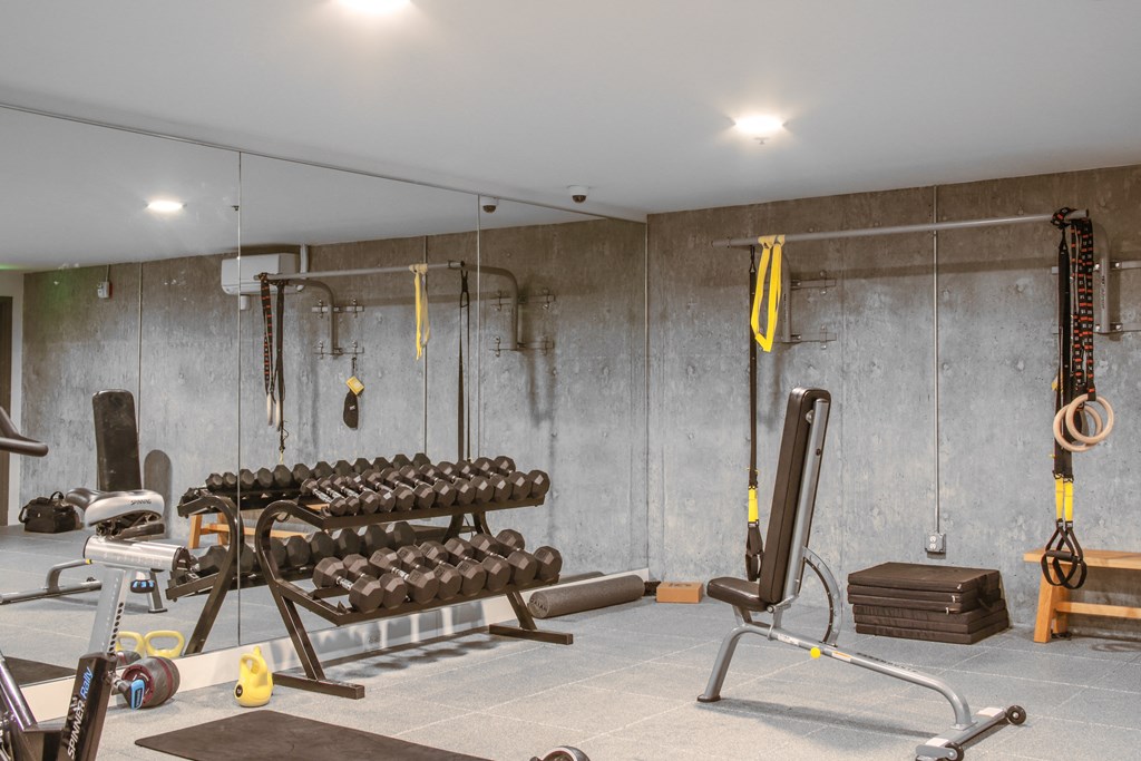 a gym with weights and other equipment in a room with concrete walls