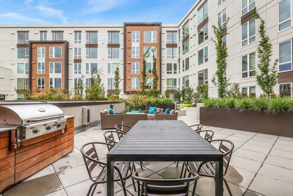 a patio with a table and chairs and a grill
