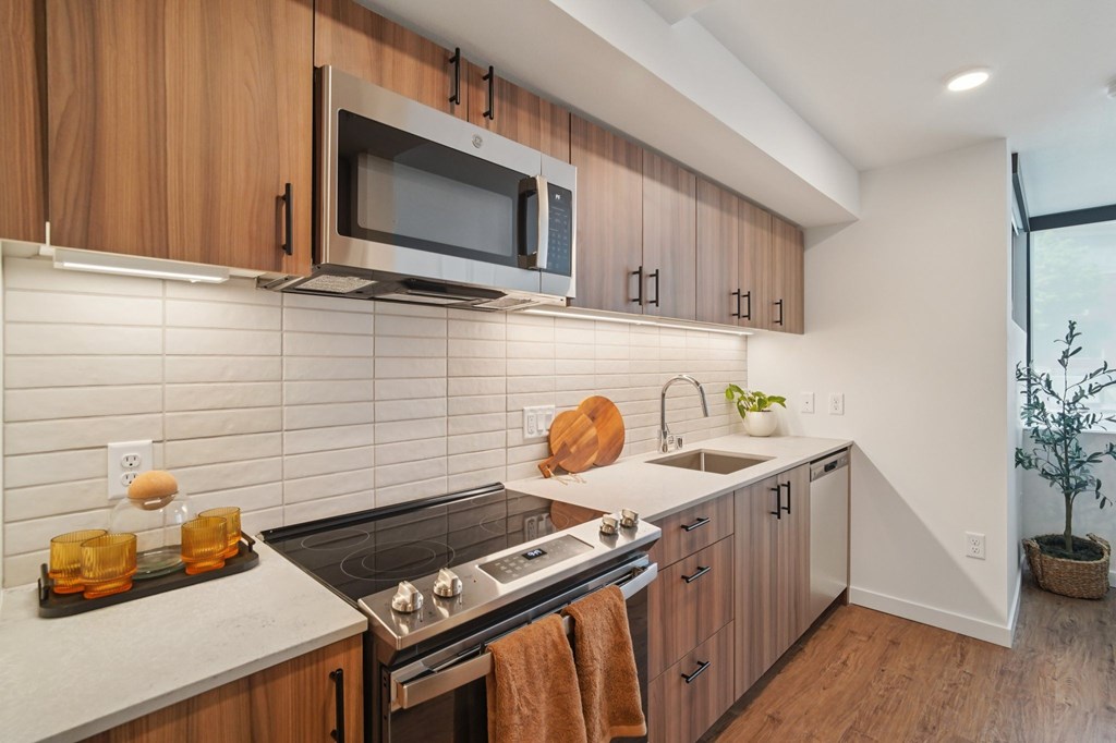 A modern kitchen with wooden cabinets and a stainless steel stove top.