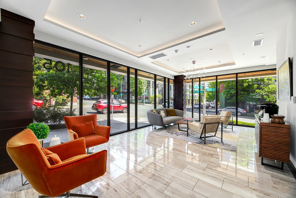 a lobby of a hotel with orange chairs and glass doors