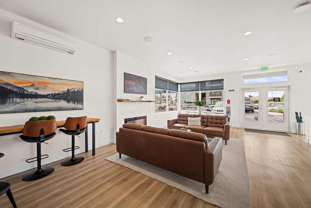 A living room with a brown couch and a painting on the wall.