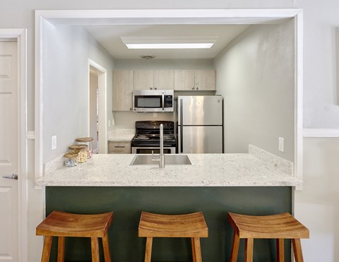 a kitchen with a marble counter top and three wooden stools