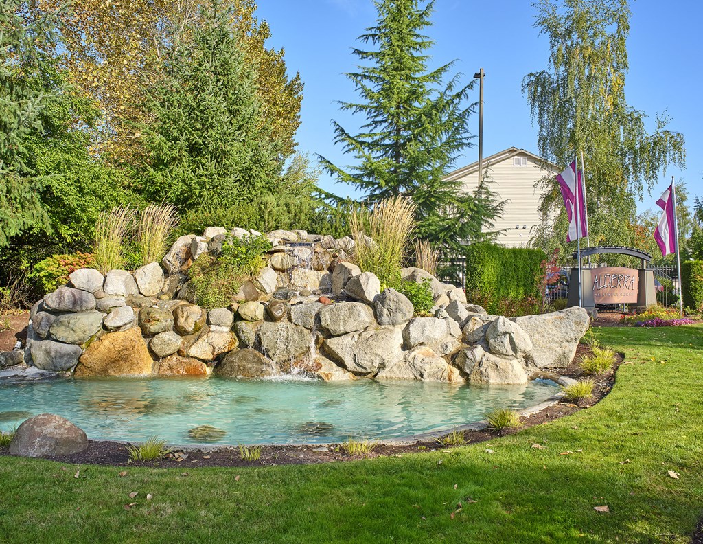 a pool of water next to a rock waterfall