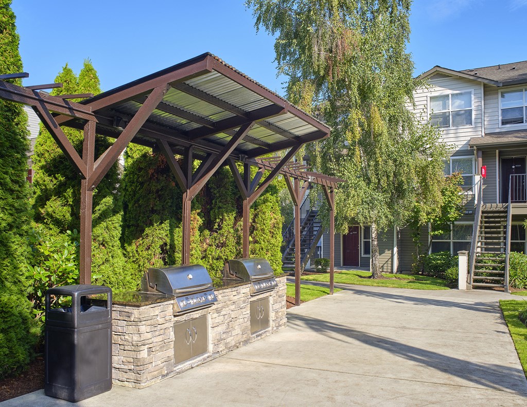 a covered picnic area with two trash bins in front of a building