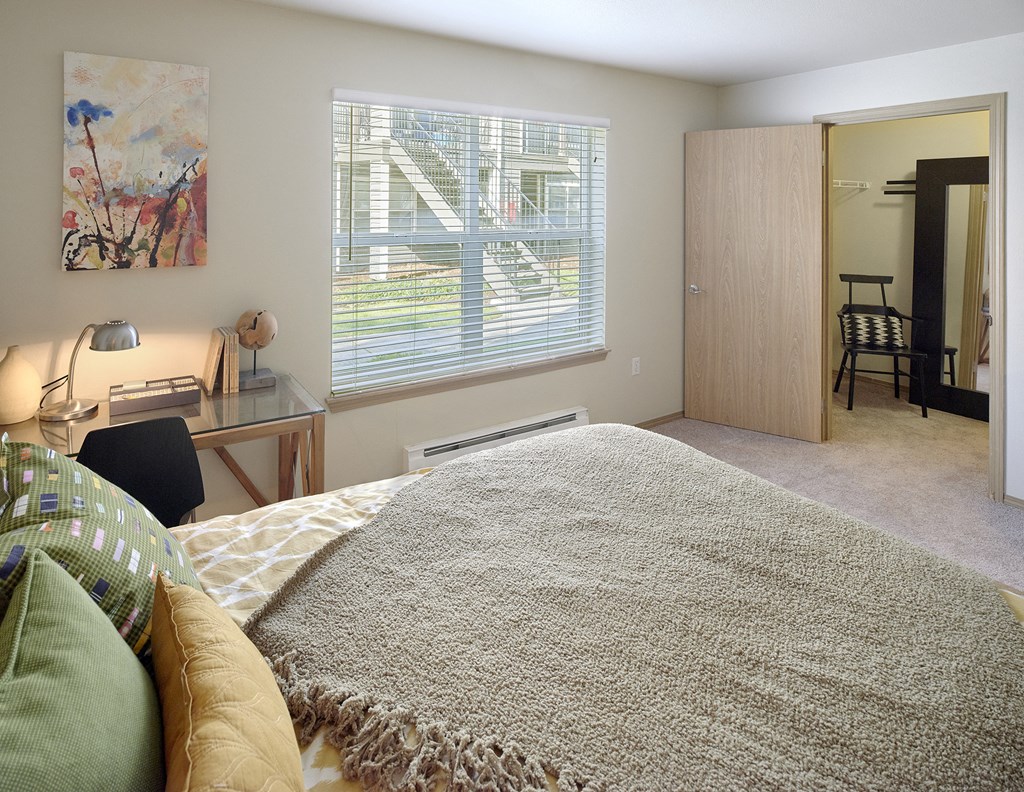 a bedroom with a bed and a desk and a window