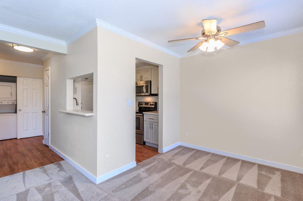an empty living room and kitchen with a ceiling fan