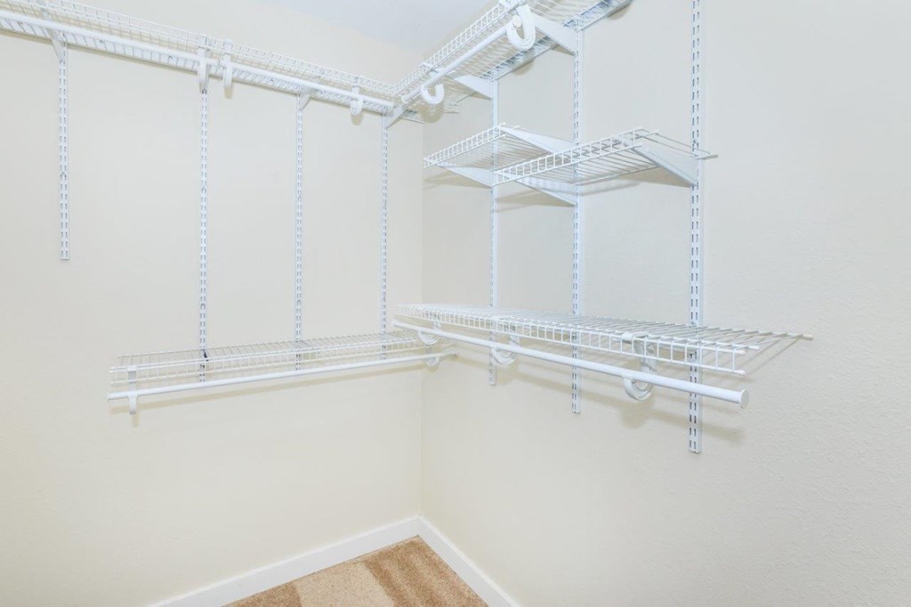 a spacious closet with white shelves and white walls
