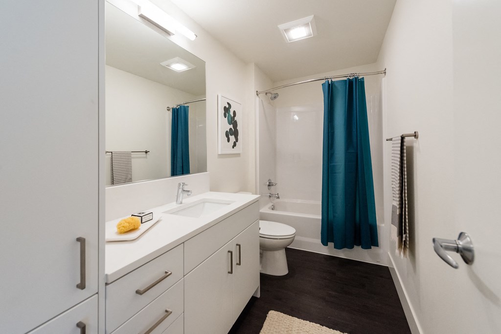 a bathroom with white cabinets and a blue shower curtain