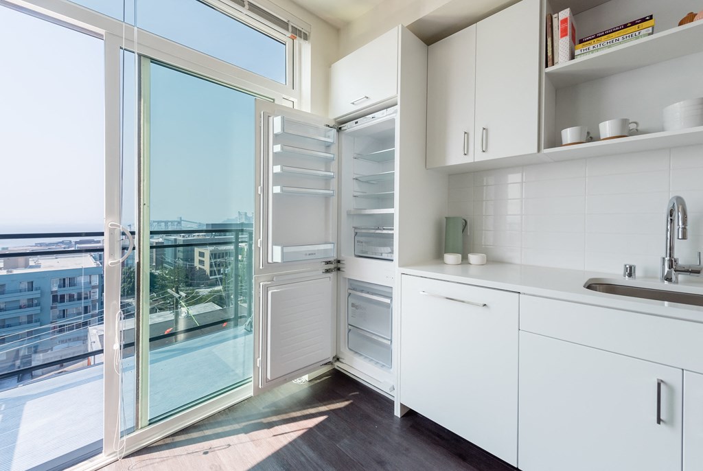 a kitchen with white cabinets and a sliding glass door that leads to a balcony