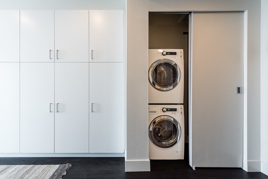 a front load washer and dryer in a laundry room with white cabinets