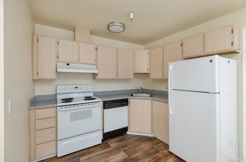 A kitchen with white appliances and wooden cabinets.