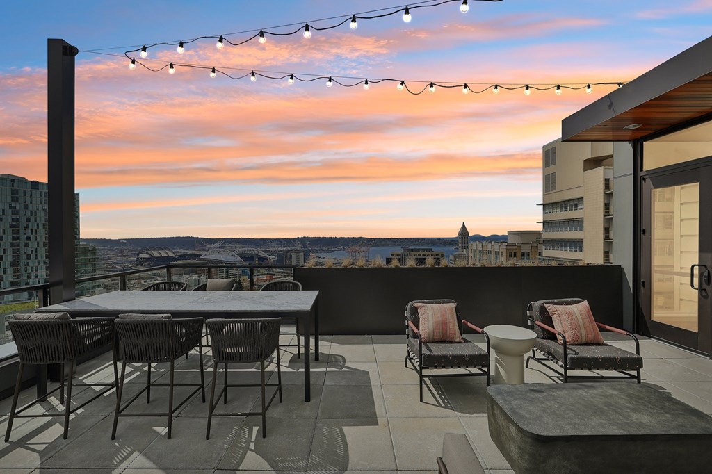 A patio with a table, chairs, and string lights.