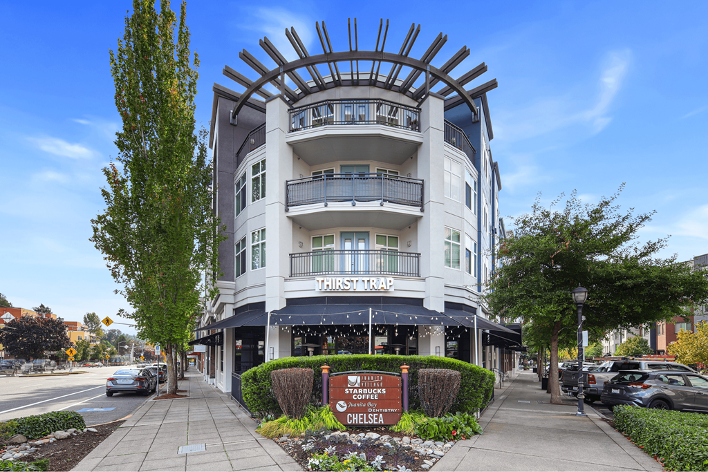 A large white building with a curved balcony and a sign that says "Hair Salon" in front of it.