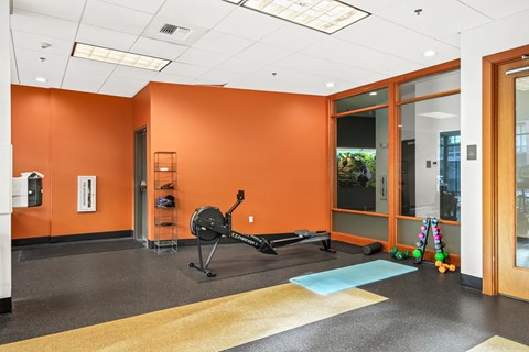 A gym with orange walls and a rowing machine.