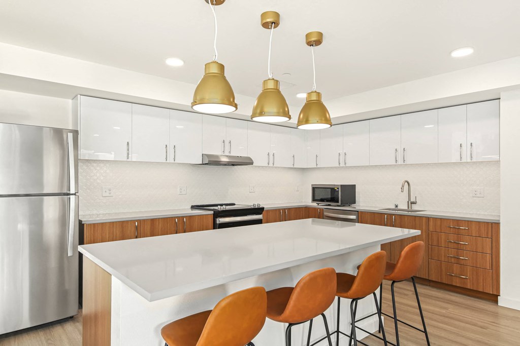 A modern kitchen with a white island and orange chairs.