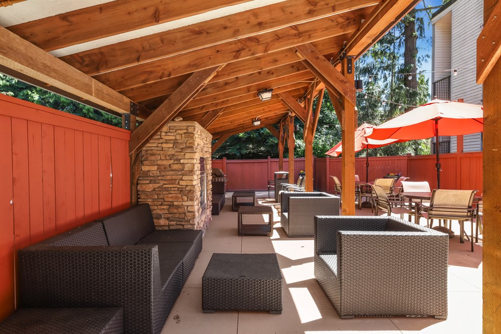 A patio with a stone pillar and a red umbrella.
