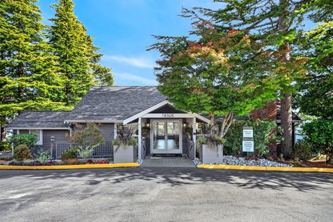 A house with a grey roof and a sign that says 1850 is surrounded by trees.