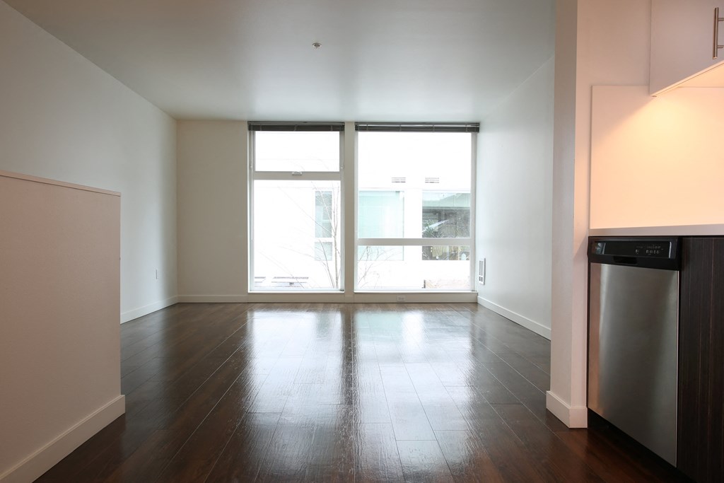an empty living room with a large window and wood floors