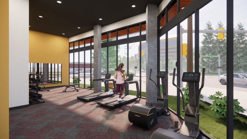 a woman sits on a treadmill in a gym with large windows