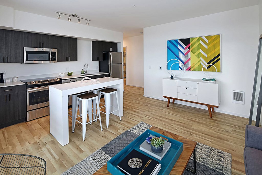A modern kitchen with a white island and a painting on the wall.