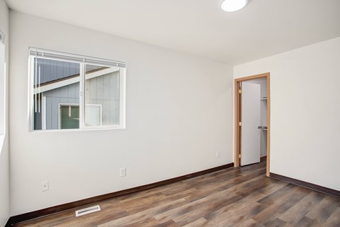 A room with a wooden floor and a window with a view of a building.