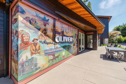A mural on a building's exterior wall depicts a lively scene with multiple figures and elements of a town.