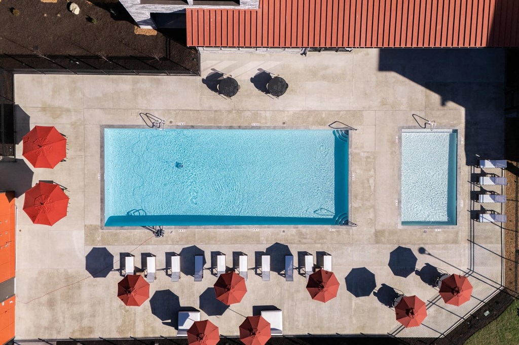 arial view of a swimming pool with umbrellas and tables on a building