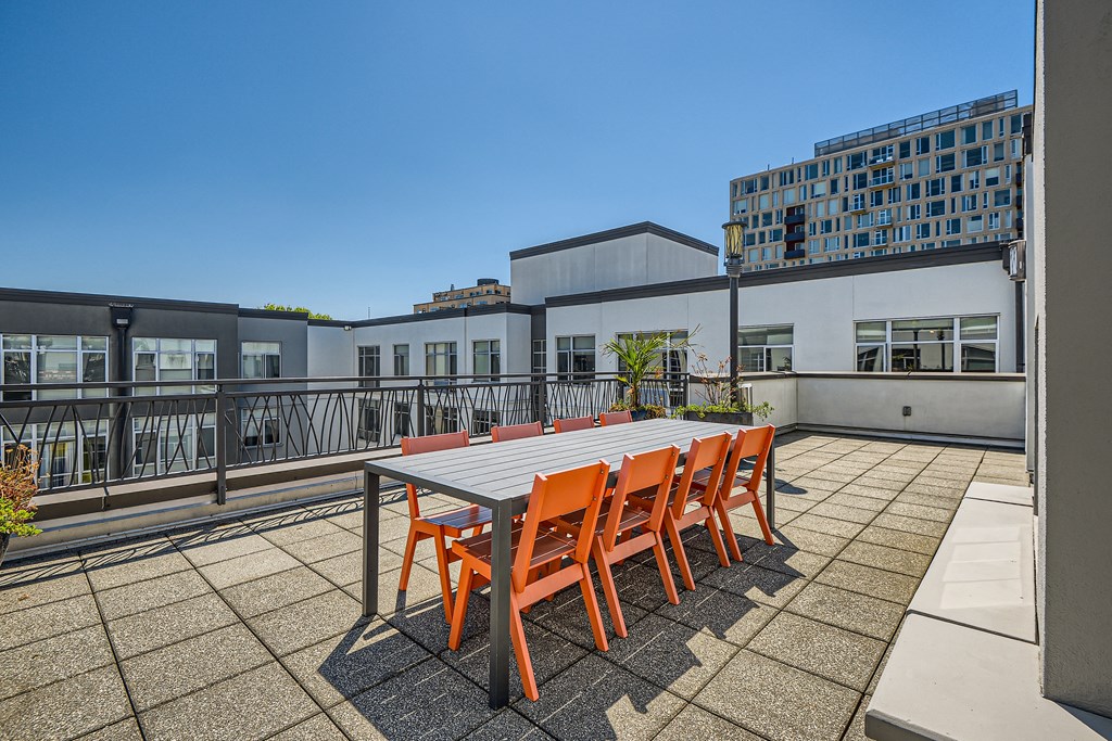 a dining table and chairs on a roof terrace with buildings in the background
