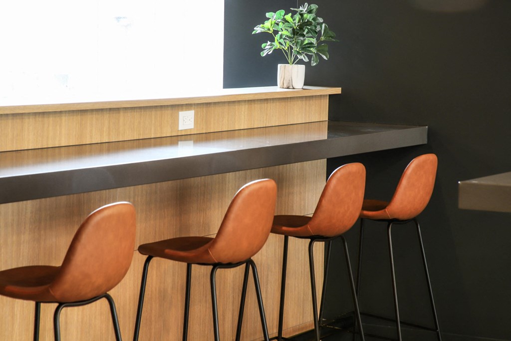 a row of orange chairs in front of a counter with a plant