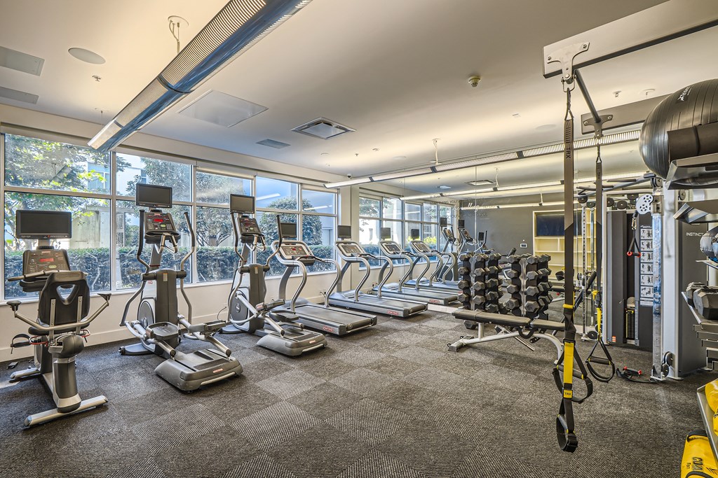 a gym with cardio equipment and windows in a building