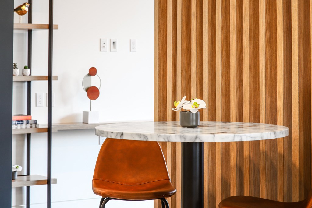 a marble table with an orange chair and a wooden wall