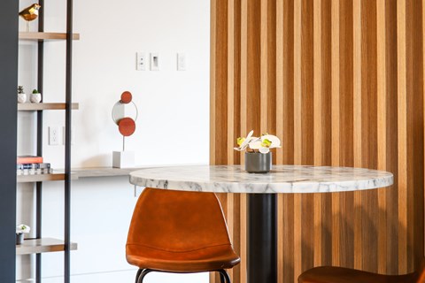 a marble table with an orange chair and a wooden wall
