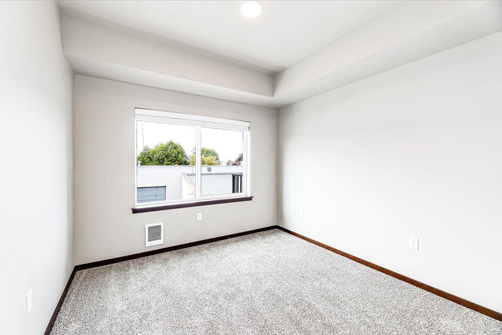 an empty room with a large window and carpet