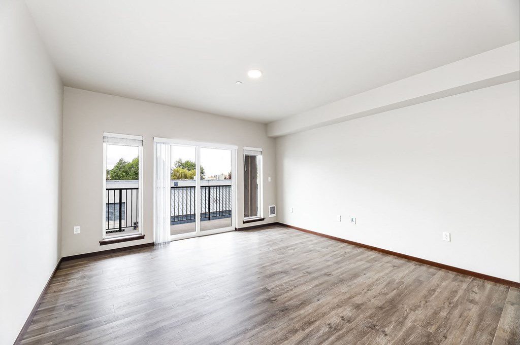 a living room with white walls and wood floors and a balcony