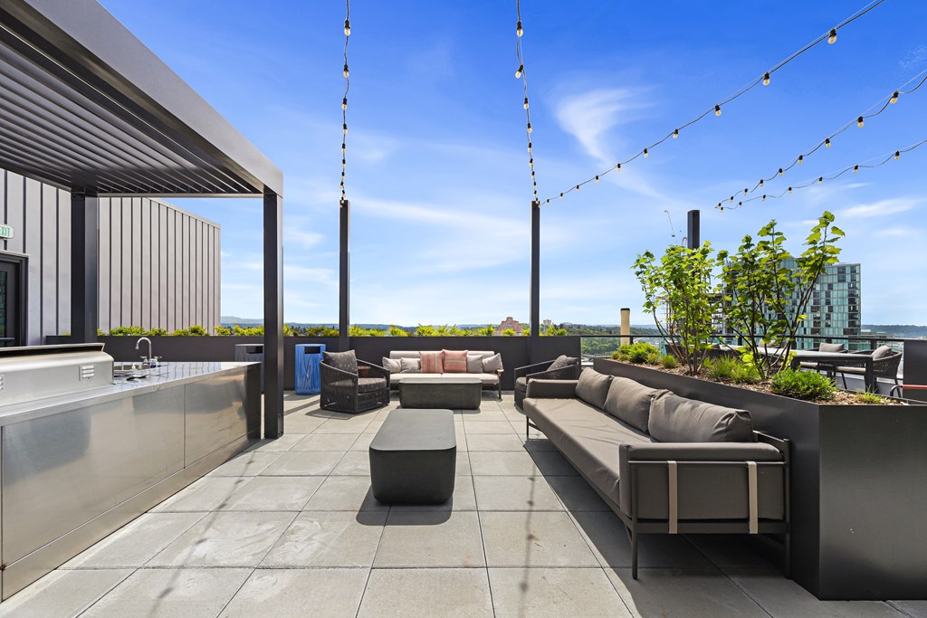 A rooftop patio with a long bench and a table.