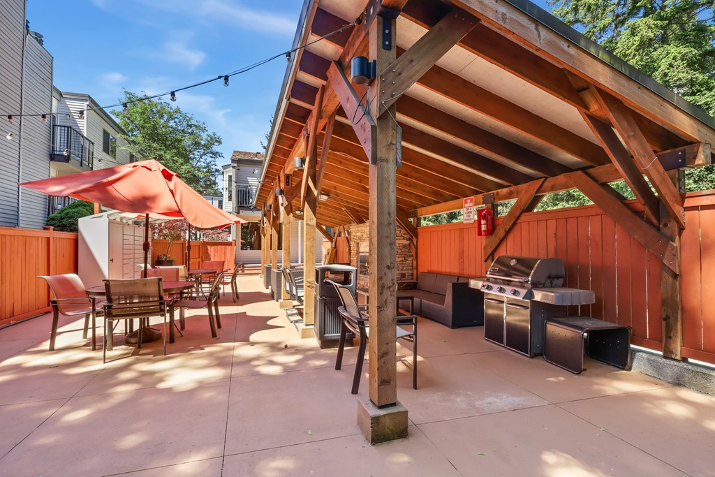 A wooden pergola with a grill and seating area.