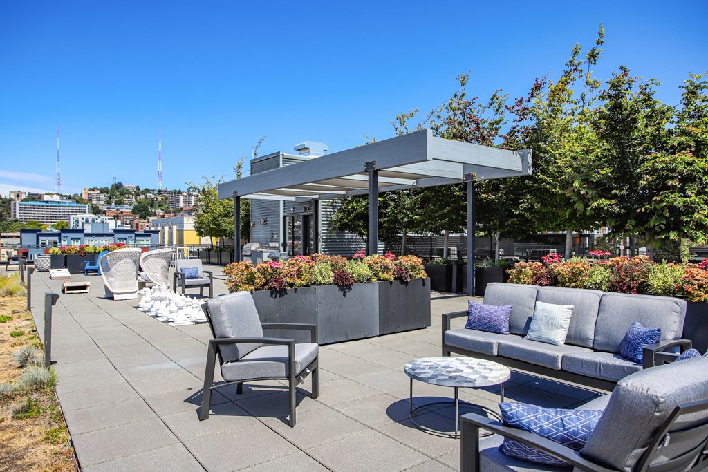 a roof top patio with couches and chairs and a pergola