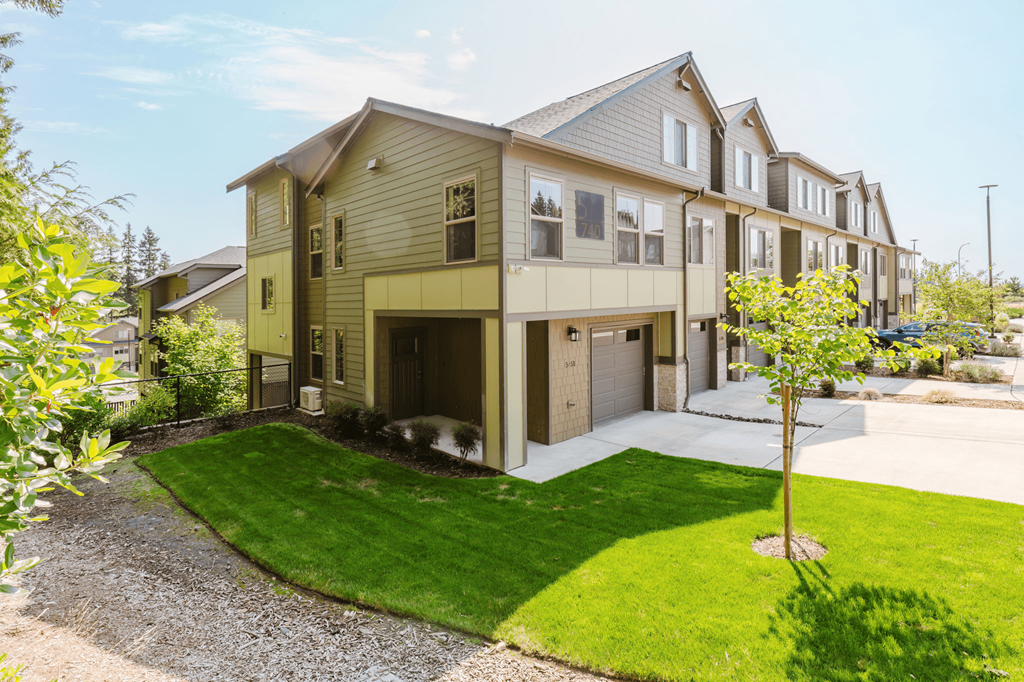 A house with a brown roof and a green lawn in front.