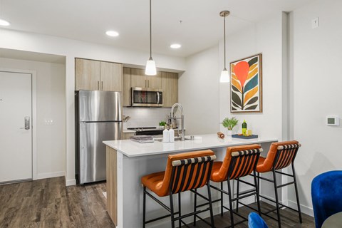 a kitchen with an island with stools and a stainless steel refrigerator