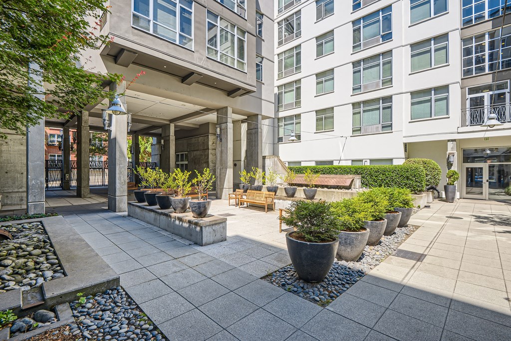 a courtyard with potted plants and a bench in front of a building