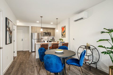 a dining area with a table and chairs and a kitchen with a refrigerator