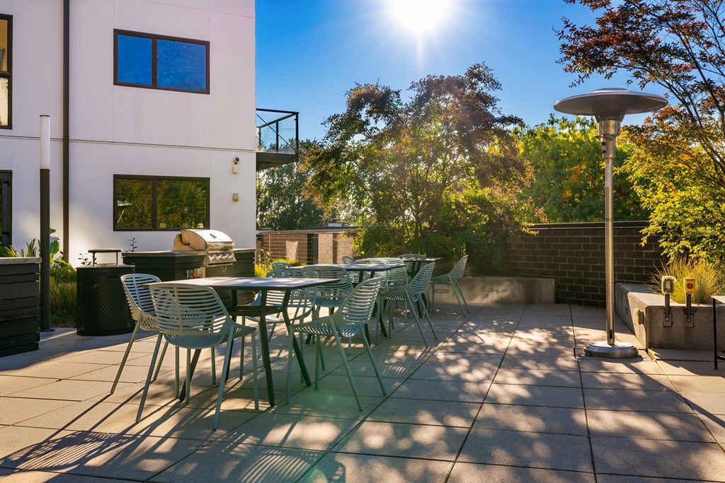 A sunny day at a patio with a table and chairs.