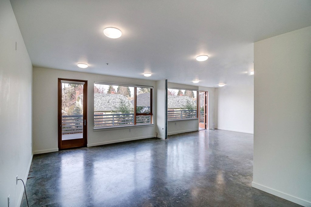 an empty living room with large windows and a concrete floor