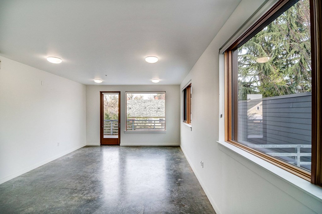 a living room with a large window and a concrete floor
