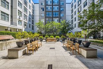 an outdoor patio with benches and potted plants in front of an apartment building