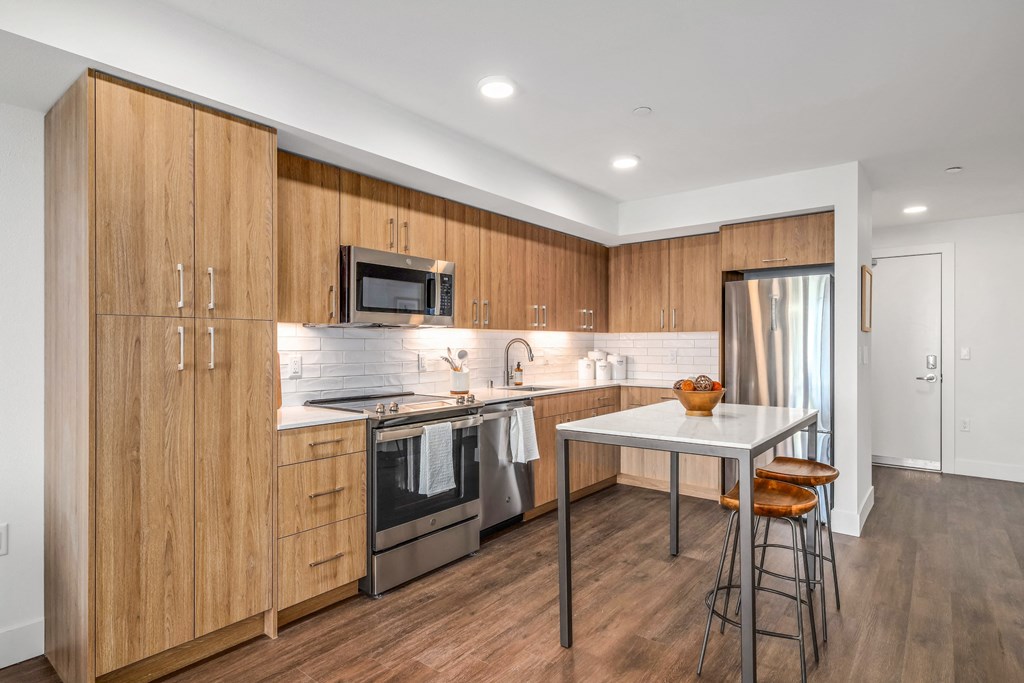 a kitchen with wooden cabinets and stainless steel appliances and a white counter top