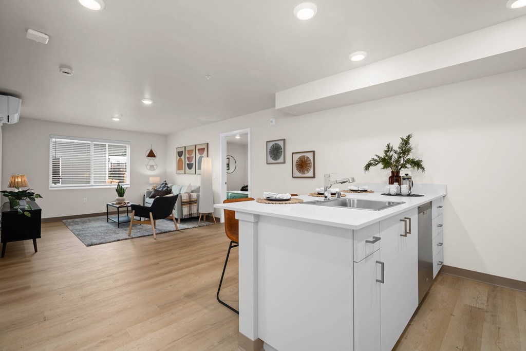 A modern kitchen with white cabinets and a wooden floor.
